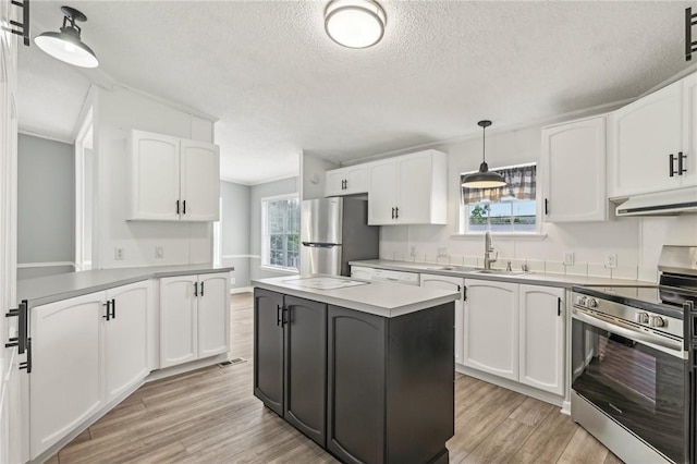kitchen featuring light wood-style flooring, a sink, white cabinetry, under cabinet range hood, and appliances with stainless steel finishes