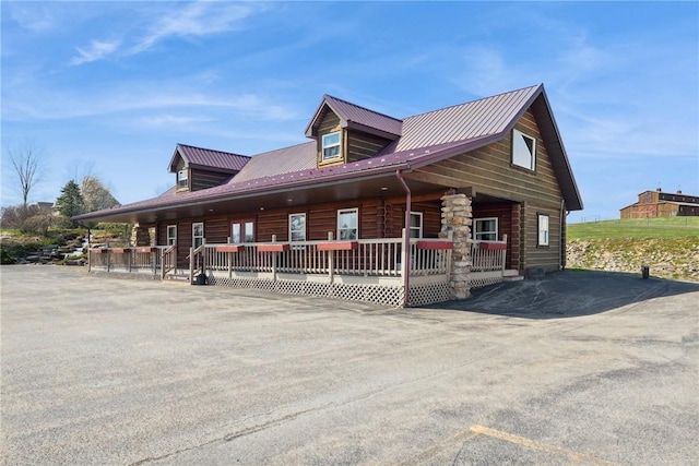 view of front of home featuring a porch, log siding, and metal roof