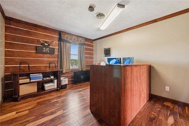 office with ornamental molding, visible vents, wood walls, and hardwood / wood-style floors