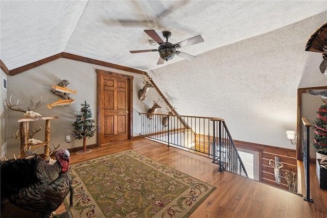 bonus room featuring lofted ceiling, ceiling fan, a textured ceiling, and wood finished floors