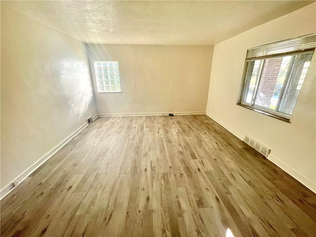 spare room with baseboards, visible vents, and wood finished floors