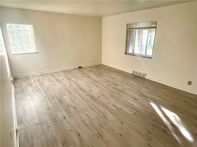 unfurnished room with baseboards, visible vents, and wood finished floors