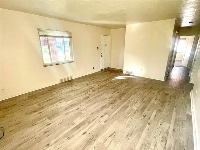 unfurnished room with baseboards, visible vents, and wood finished floors