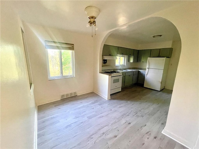 kitchen featuring white appliances, wood finished floors, visible vents, arched walkways, and baseboards