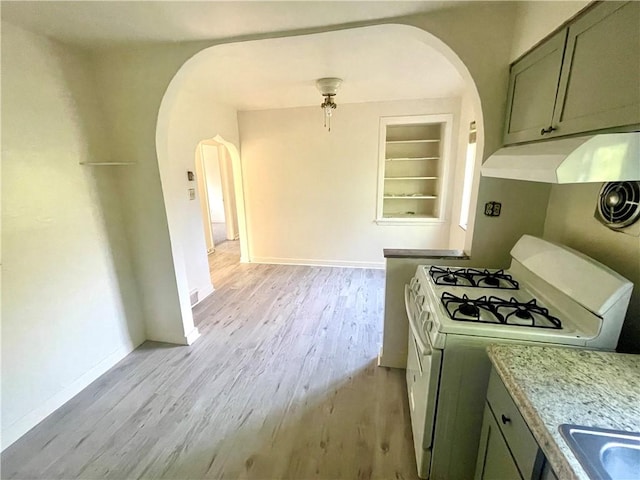 5850 Heberton Dr, Penn Hills, PA 15147 - kitchen featuring arched walkways, white gas range, under cabinet range hood, light wood-style flooring, and baseboards