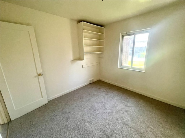 empty room with carpet, visible vents, and baseboards