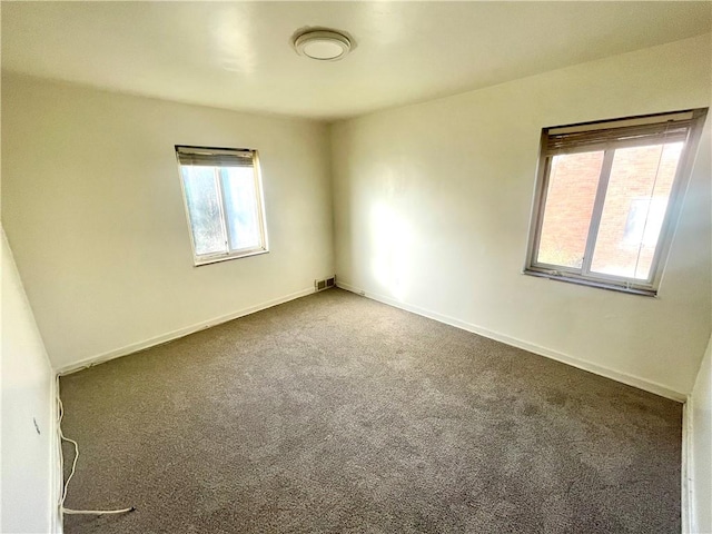 carpeted empty room with a wealth of natural light, baseboards, and visible vents