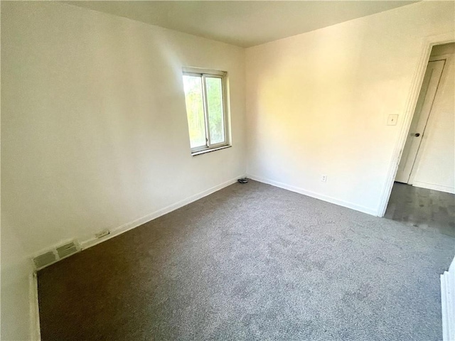 unfurnished room with dark colored carpet, baseboards, and visible vents