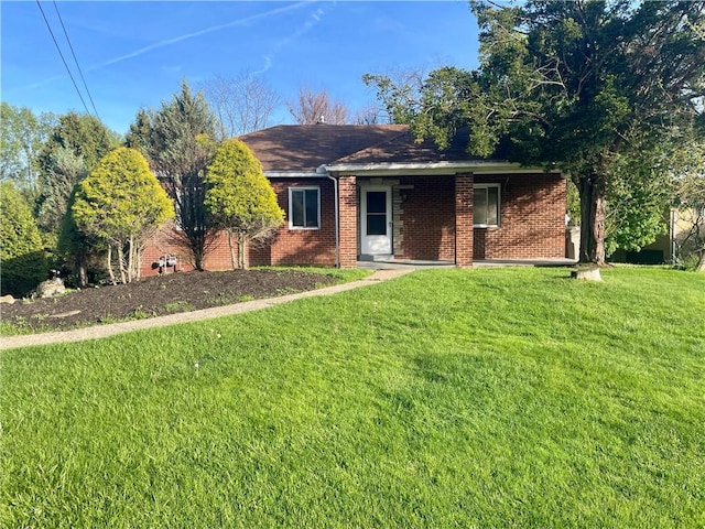 single story home featuring a front yard, roof with shingles, and brick siding