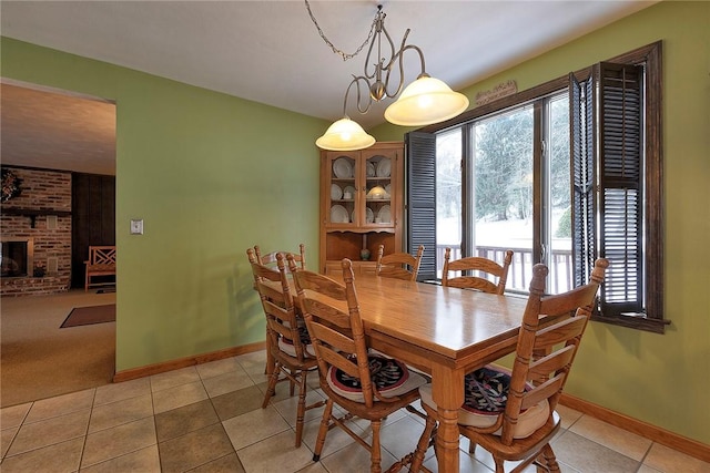 dining area featuring baseboards, light tile patterned flooring, and a brick fireplace