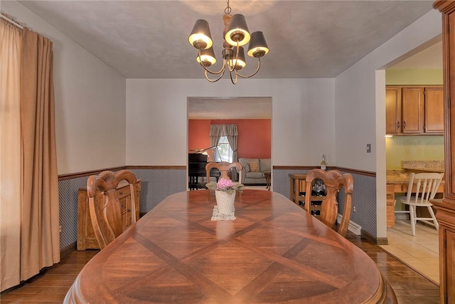 dining area with a notable chandelier, wainscoting, and dark wood-style floors