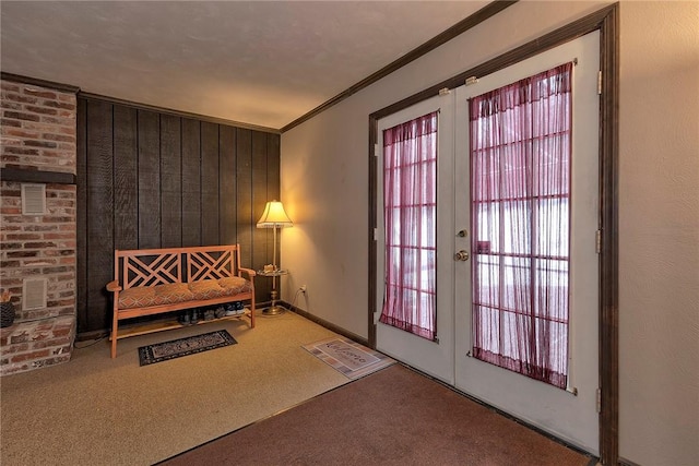 sitting room featuring ornamental molding, wood walls, carpet floors, and french doors