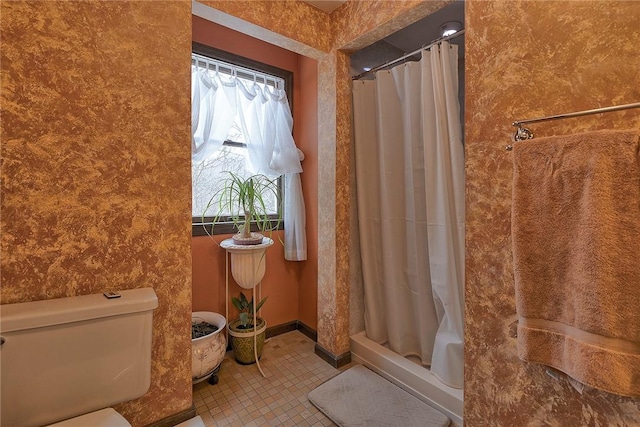 bathroom with tile patterned floors, toilet, and a shower stall