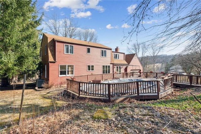 back of property featuring cooling unit, a shingled roof, a chimney, and a wooden deck