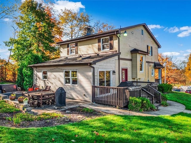 back of house with a deck, a patio area, and a lawn