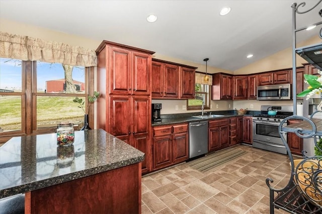 kitchen featuring a sink, dark stone counters, decorative light fixtures, appliances with stainless steel finishes, and lofted ceiling