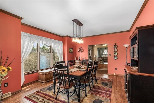 dining area featuring a healthy amount of sunlight, ornamental molding, and hardwood / wood-style flooring