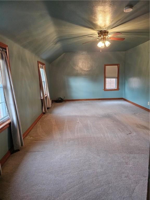 additional living space with ceiling fan, a wealth of natural light, and light colored carpet