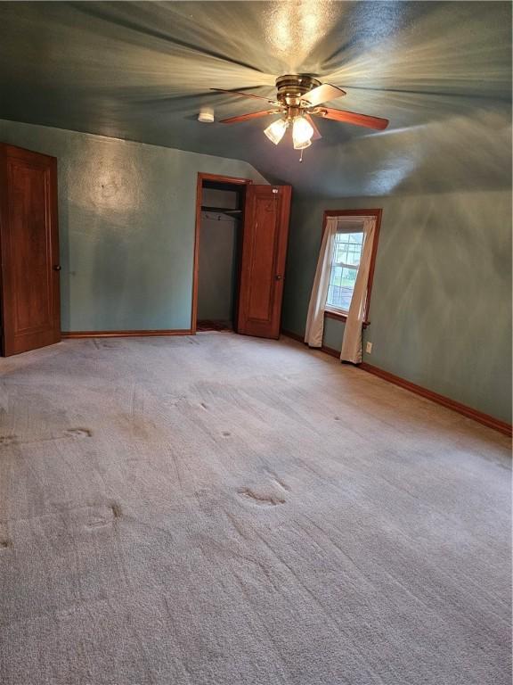 unfurnished bedroom with vaulted ceiling, baseboards, a ceiling fan, and light carpet