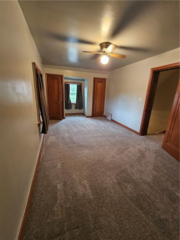 unfurnished bedroom with light carpet, baseboards, and ceiling fan