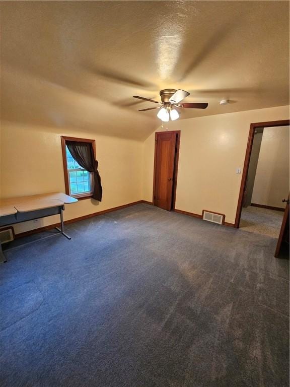 interior space with a ceiling fan, dark colored carpet, baseboards, and visible vents
