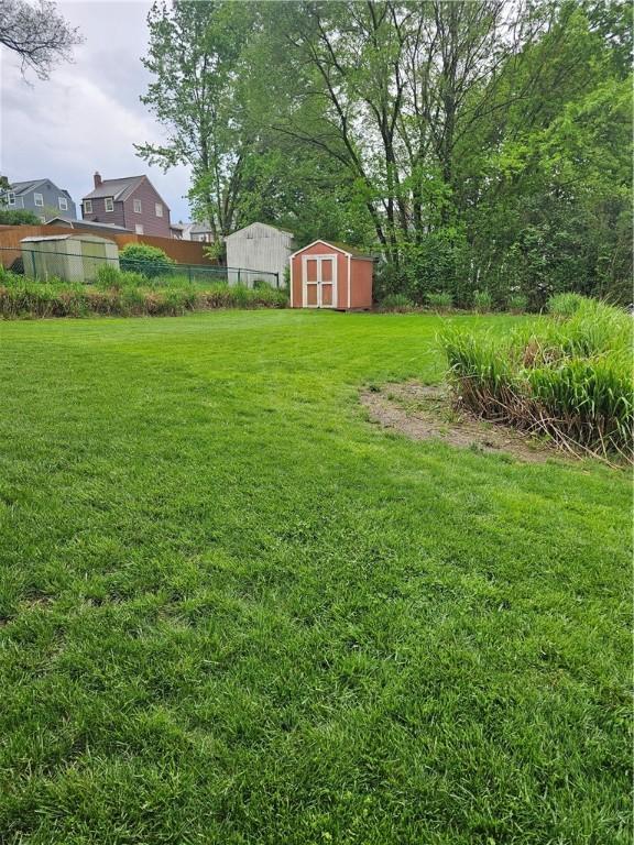view of yard with a storage shed, an outdoor structure, and fence