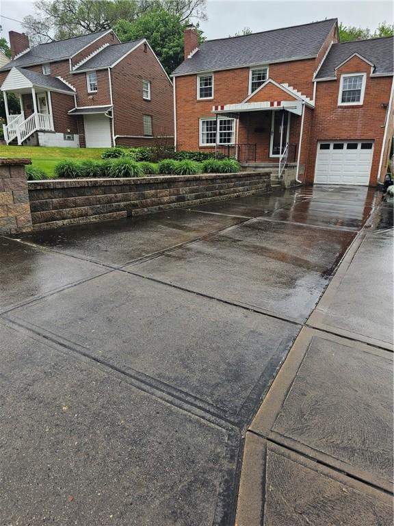 view of front of property featuring concrete driveway, a chimney, brick siding, and an attached garage