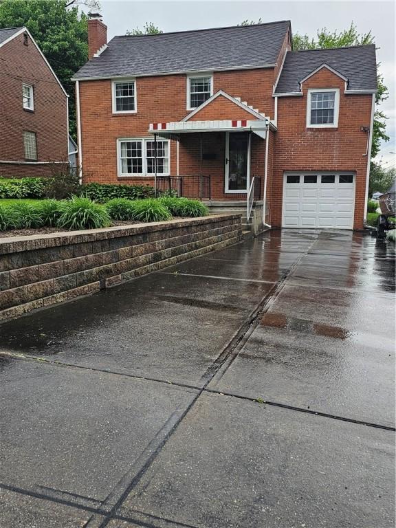 view of front facade featuring a chimney, driveway, brick siding, a garage, and a porch