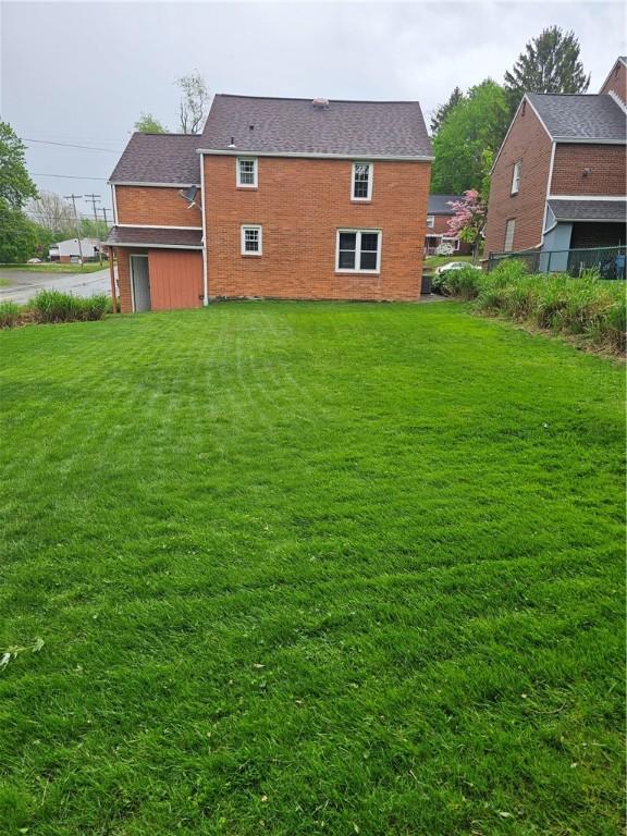 rear view of house with brick siding and a lawn