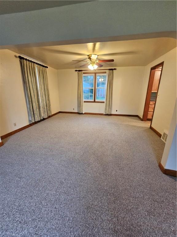 spare room featuring carpet flooring, visible vents, baseboards, and a ceiling fan