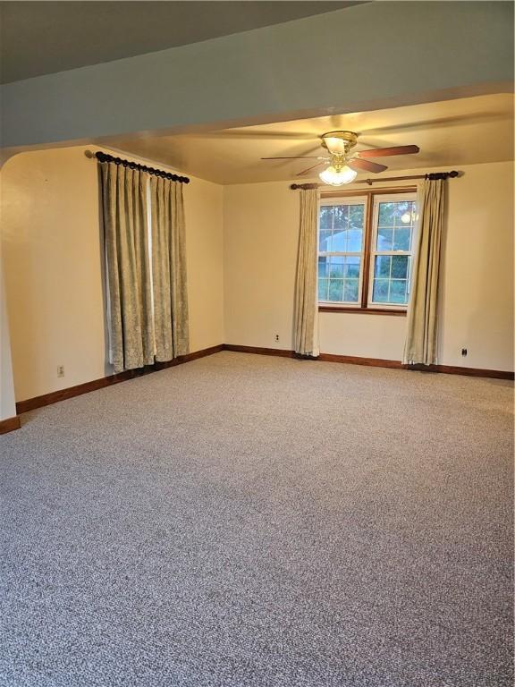 spare room featuring baseboards, ceiling fan, light colored carpet, and arched walkways