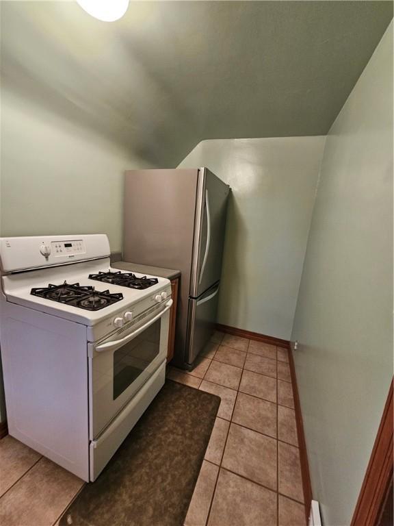 kitchen featuring white gas range oven, freestanding refrigerator, and light tile patterned floors