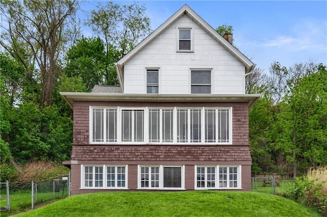 back of property with a lawn, a chimney, and fence
