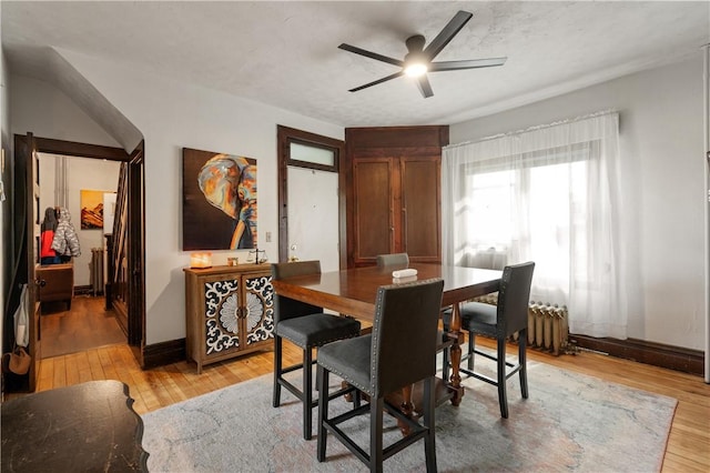 dining space featuring radiator, baseboards, a ceiling fan, and light wood-style floors