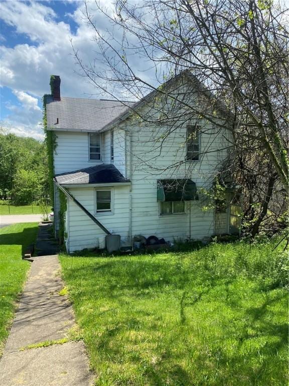 view of side of property with a chimney and a lawn