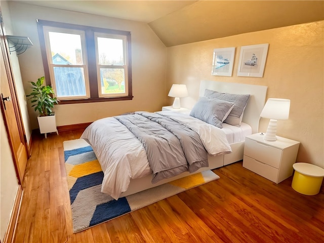 bedroom with wood finished floors and vaulted ceiling