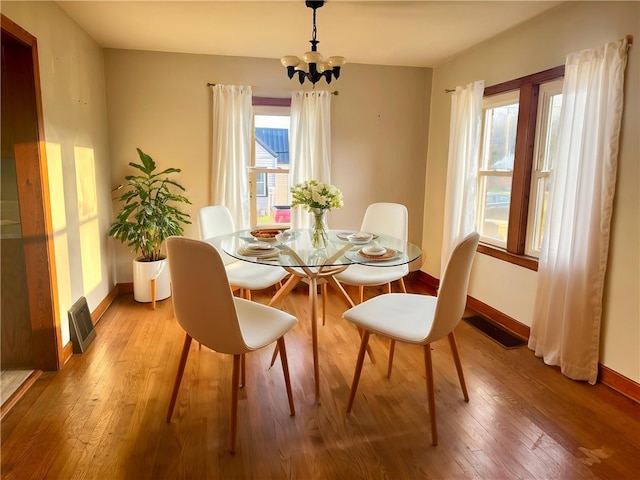 dining area featuring baseboards, a wealth of natural light, light wood finished floors, and an inviting chandelier