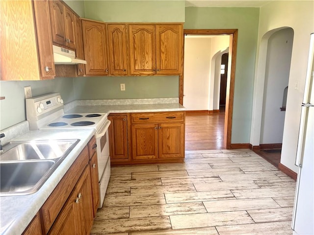 kitchen with a sink, under cabinet range hood, light wood finished floors, arched walkways, and white electric stove