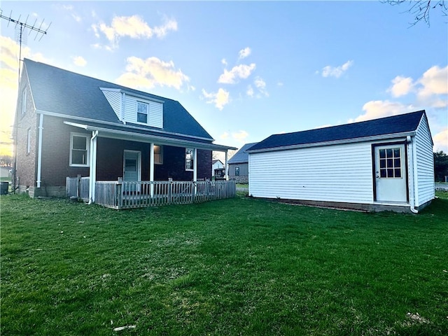 back of house featuring a porch, brick siding, and a lawn