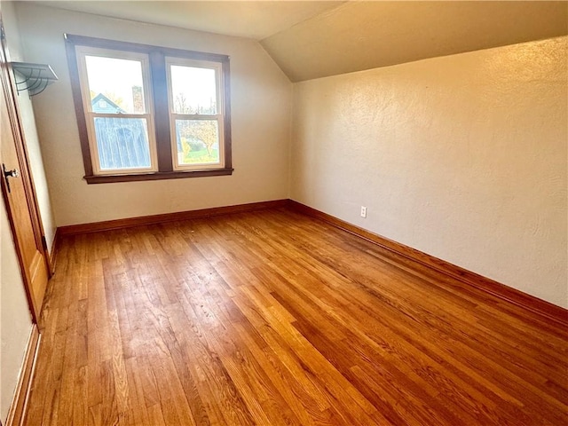 bonus room with lofted ceiling, baseboards, and light wood-type flooring