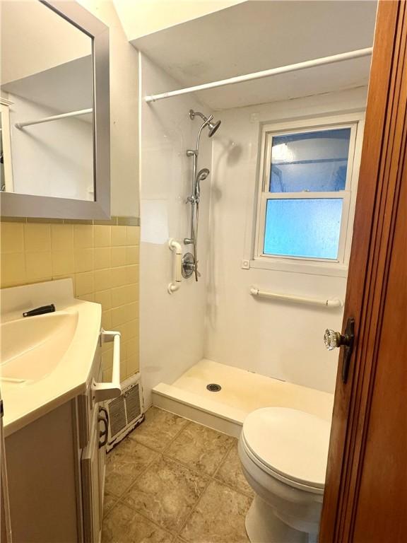 full bath featuring toilet, tile patterned floors, tile walls, a shower stall, and vanity