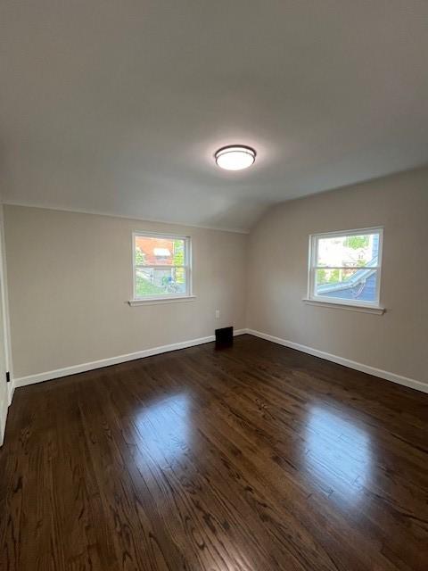 additional living space featuring dark wood-type flooring, baseboards, and lofted ceiling