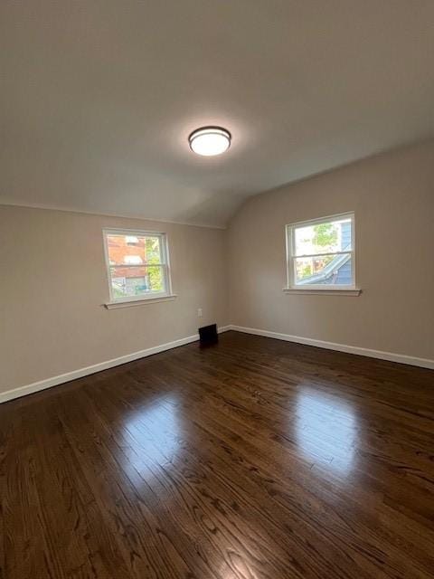 additional living space with vaulted ceiling, dark wood-style flooring, and baseboards