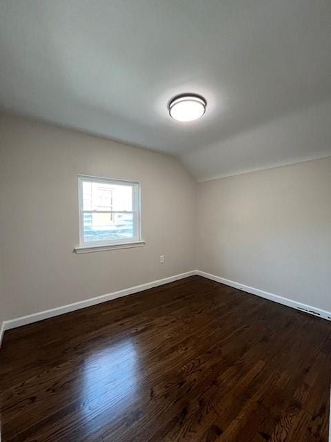 additional living space featuring dark wood-style flooring, baseboards, and lofted ceiling