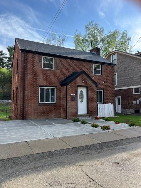 view of front facade with a chimney and brick siding