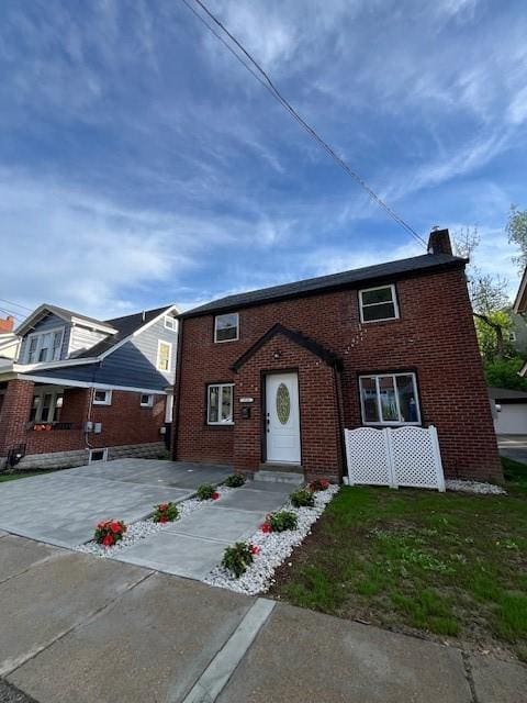 view of front of property featuring a chimney and brick siding