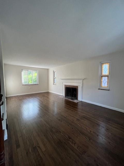 unfurnished living room with a fireplace with flush hearth, baseboards, and dark wood-type flooring