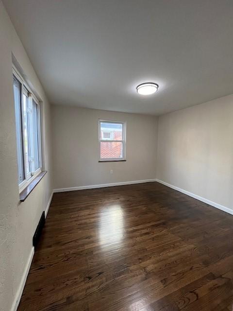 unfurnished room featuring dark wood-style flooring and baseboards