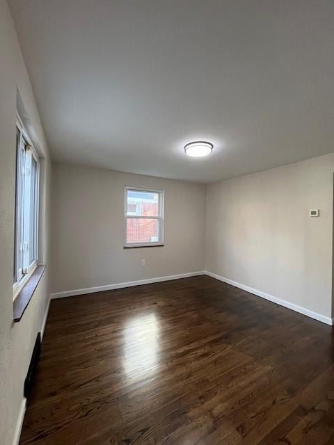 empty room featuring baseboards and dark wood finished floors