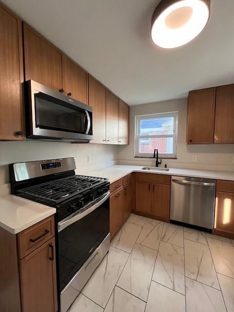 kitchen featuring a sink, stainless steel appliances, light countertops, and marble finish floor